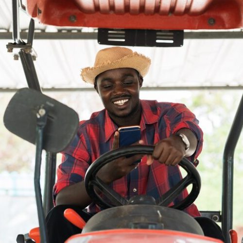 agriculteur-africain-utilisant-smartphone-conduisant-tracteur-dans-ferme-pendant-recolte-dans-campagne-concept-agriculture-culture_73622-1704